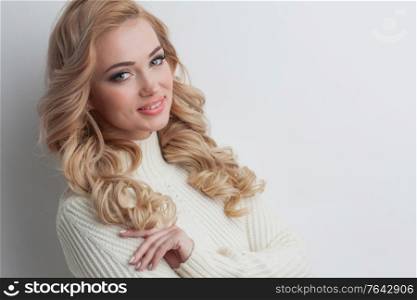 Portrait of beautiful blonde woman in white sweater, winter concept. Blond woman in white sweater