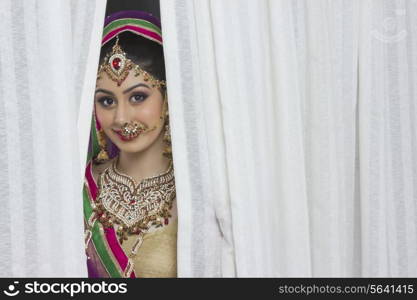Portrait of beautiful bride smiling amidst curtains