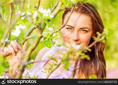 Portrait of beautiful brunette female near blooming fruit tree, spring season, enjoying nature, holiday and vacation concept