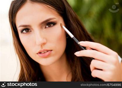 portrait of beautiful brunette girl making up