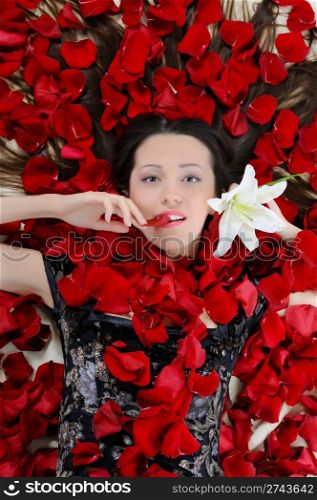 Portrait of beautiful brunette in rose petals