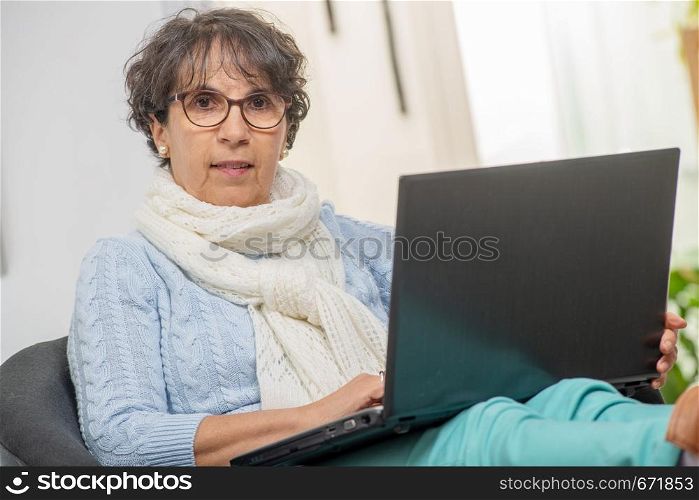 portrait of beautiful brunette mature woman with a laptop at home