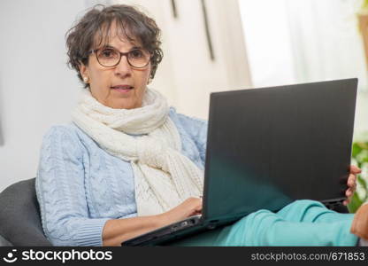 portrait of beautiful brunette mature woman with a laptop at home