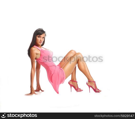 Portrait of beautiful brunette model sits on the floor in pink dress,