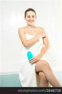 Portrait of beautiful brunette woman applying moisturizing lotion at bathroom