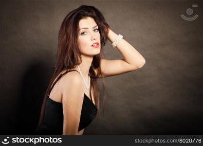 Portrait of beautiful brunette woman. Magnificent long hair woman red lipstick black dress portrait on dark