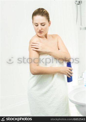 Portrait of beautiful brunette woman using lotion after bathing