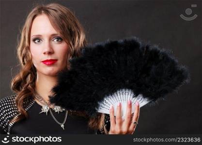 Portrait of beautiful brunette woman with black feather fan in hand