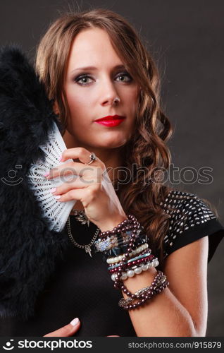 Portrait of beautiful brunette woman with black feather fan in hand