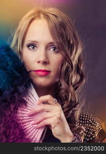 Portrait of beautiful brunette woman with black feather fan in hand on festive colorful background