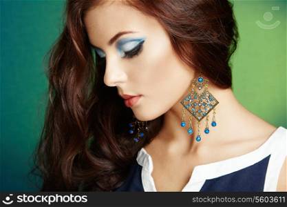 Portrait of beautiful brunette woman with earring. Perfect makeup. Fashion photo