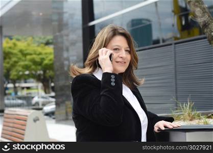 Portrait of beautiful business woman talking on her smartphone. Outdoors.. Portrait of business woman talking on her smartphone.