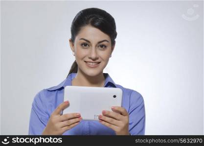 Portrait of beautiful businesswoman holding tablet PC against gray background