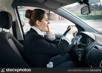 Portrait of beautiful businesswoman talking by phone while driving a car