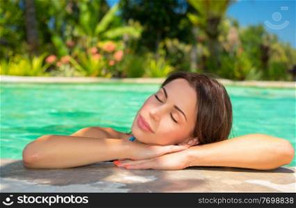 Portrait of beautiful calm woman with closed eyes relaxing in the pool, spending summer vacation on luxury spa resort