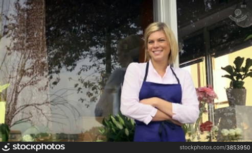 Portrait of beautiful caucasian girl self-employed in flower shop, smiling and looking at camera. Dolly shot