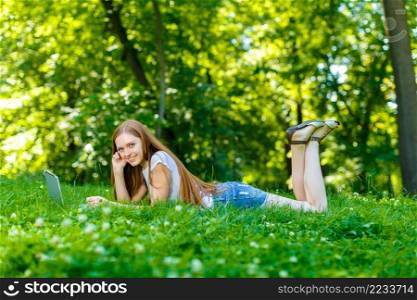 Portrait of beautiful caucasian smiling red-haired young woman, against summer green park.. Beautiful smiling red-haired young woman