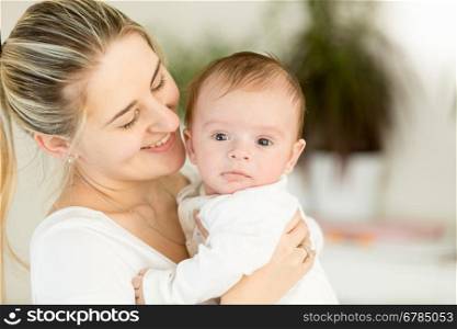 Portrait of beautiful cheerful mother embracing her 3 months old baby boy
