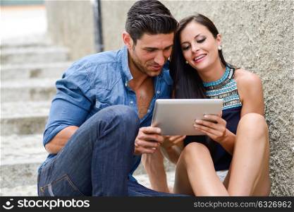 Portrait of beautiful couple with tablet computer in urban background