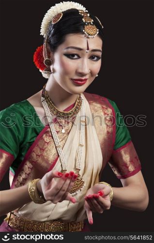 Portrait of beautiful dancer performing Bharatanatyam over black background