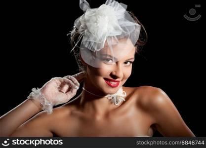 Portrait of Beautiful Elegant Bride in Wonderful Wedding Accessories: Lace Gloves, White Necklace and Fancy Hat at the Black Background.