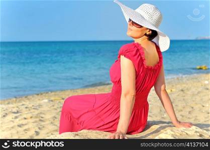 Portrait of beautiful female in red dress on beach
