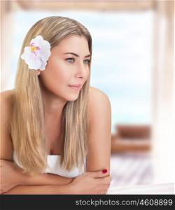 Portrait of beautiful gentle woman with orchid flower in hair waiting for massages, relaxation on luxury spa resort