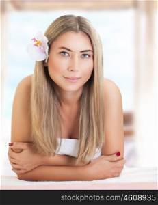 Portrait of beautiful gentle woman with orchid flower in hair waiting for massages, relaxation on luxury spa resort