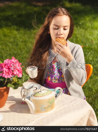 Portrait of beautiful girl having breakfast at yard and biting cookie
