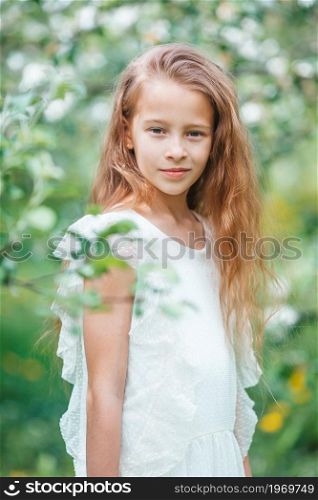 Portrait of beautiful girl in blooming apple tree garden on spring day. Adorable little girl in blooming apple garden on beautiful spring day