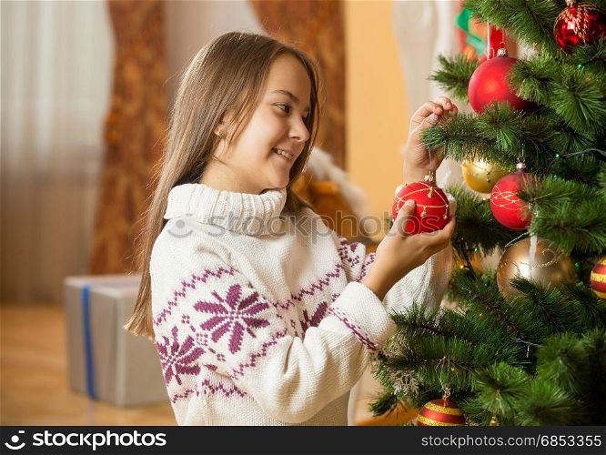 Portrait of beautiful girl in sweater decorating Christmas tree