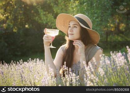 Portrait of beautiful girl is drinking  wine in lavender field