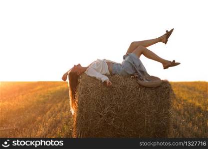 Portrait of beautiful girl on haystack roll on harvested wheat field in the summer. Selective focus. Portrait of beautiful girl on haystack roll on harvested wheat field in the summer. Selective focus.