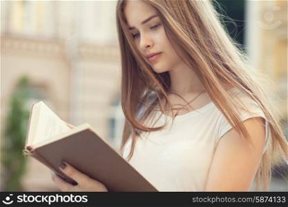 portrait of beautiful girl reading outdoors