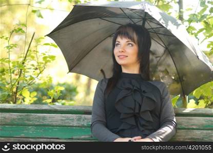 Portrait of beautiful girl with umbrella sitting in the park