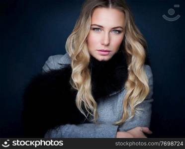 Portrait of beautiful gorgeous woman with natural makeup  wearing stylish coat with fur scarf over black background, fashion and vogue concept