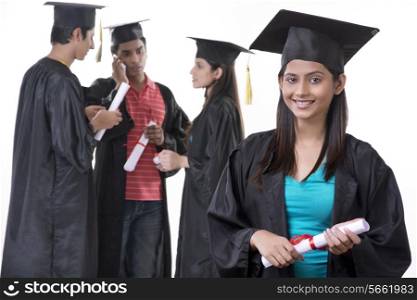 Portrait of beautiful graduate student with friends discussing against white background