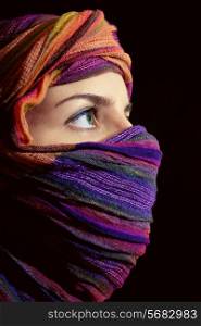 Portrait of beautiful green-eyed woman in hijab on black background