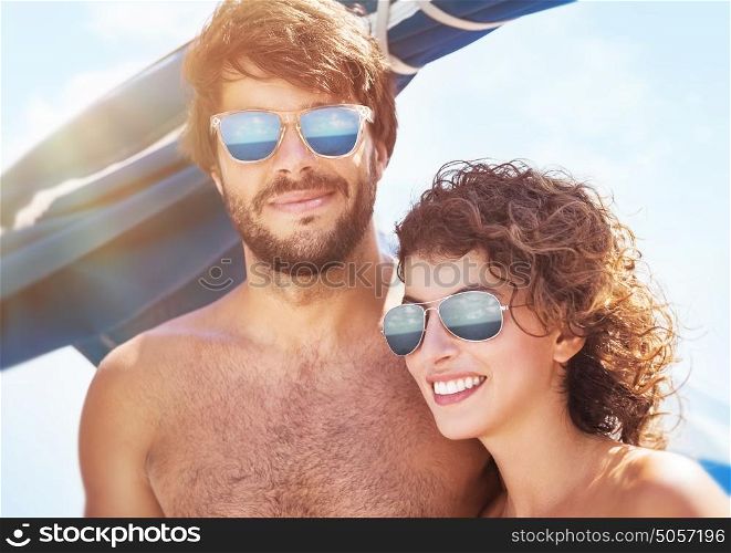 Portrait of beautiful happy couple in bright sunny day spending time on a sailboat, joyful young family enjoying summer adventure