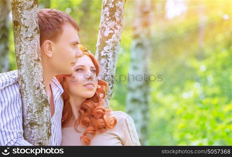 Portrait of beautiful happy couple in love, standing and hugging between birch trees and enjoying bright sun light, romantic relationship concept