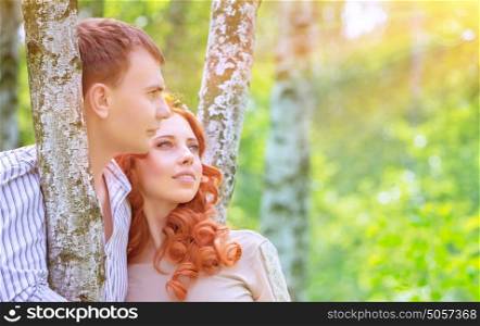 Portrait of beautiful happy couple in love, standing and hugging between birch trees and enjoying bright sun light, romantic relationship concept