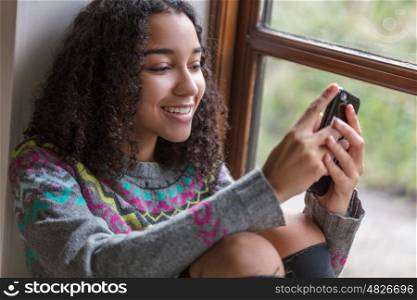 Portrait of beautiful happy mixed race African American girl teenager female young woman smiling with perfect teeth using mobile cell phone for social media or texting,