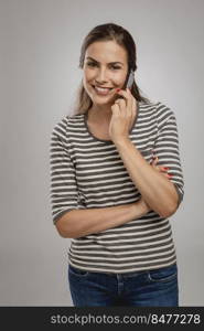 Portrait of beautiful happy young woman over a gray background making a phone call