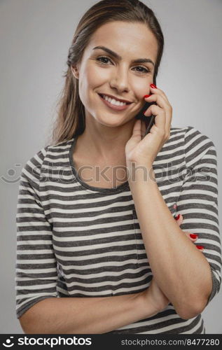 Portrait of beautiful happy young woman over a gray background making a phone call