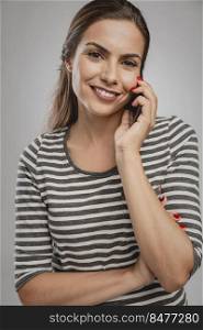 Portrait of beautiful happy young woman over a gray background making a phone call
