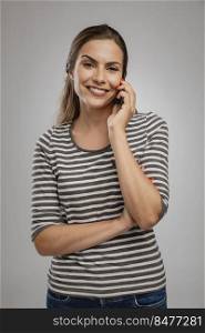 Portrait of beautiful happy young woman over a gray background talking at phone 