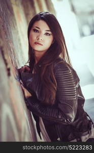 Portrait of beautiful japanese woman in urban background wearing leather jacket