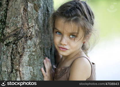 Portrait of beautiful little girl, against background of summer park