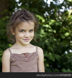 Portrait of beautiful little girl, against background of summer park