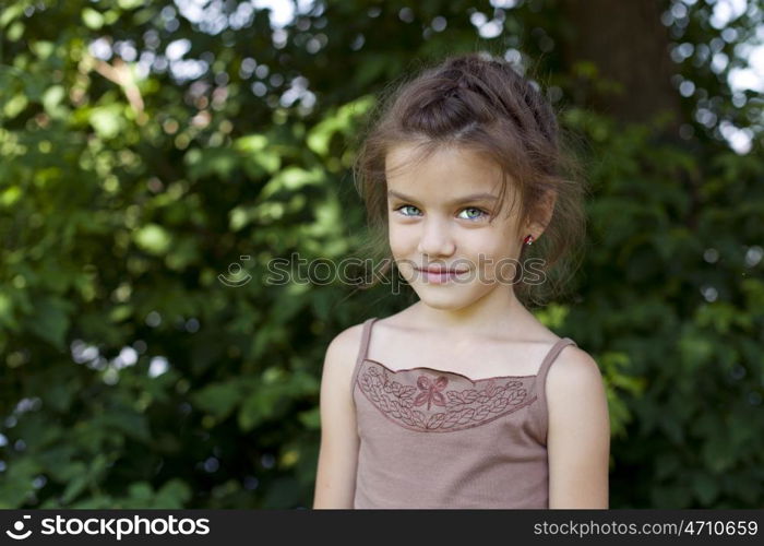 Portrait of beautiful little girl, against background of summer park